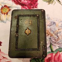 Closed green metal coin bank with safe door design and some age wear