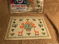 Close-up of the paper placemat design showing deer, birds, flowers, and decorative border.