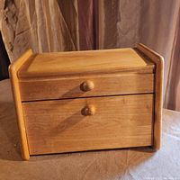 Front view of wooden bread box showing drawer and hinged drop-down door closed