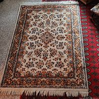 Full view of the vintage wool rug showing overall floral and border design, fringed edges, and condition.