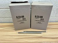 Two sealed cardboard boxes labeled '7.75" Jumbo Straw Cello Wrap 500 Black' with two example straws placed in front, one straw sealed in cello wrap and one unwrapped to show size and appearance.