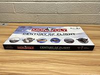 Closed game box with Century of Flight Monopoly branding and aviation images on the cover and sides.