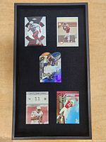 Five Larry Fitzgerald rookie football cards displayed in a black framed case with felt backing.