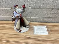 Full view of the Lenox porcelain figurine 'A Christmas Traveler' showing Santa holding a red cardinal bird with a snowy base and certificate.