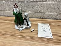 Full view of Lenox Santa's Gift of Peace figurine standing on snowy base with animals including polar bear and penguin, accompanied by informational insert booklet.
