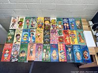 33 vintage 1970s greeting cards with cartoon-style illustrations laid out on a wooden table, showing colorful designs and humorous texts.