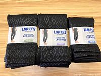 Three pairs of black fleece-lined leggings, each wrapped with branded Lukees by MUK LUKs packaging showing front with label and front diamond patterned design.