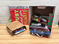 Lot of assorted Christmas gift bags, wrapping paper rolls, and ribbons with festive colors and themes.