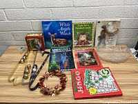 Photo of all books, wreath hangers, decorative small wreath, and large leaf-shaped mold arranged on a table against a white brick wall.