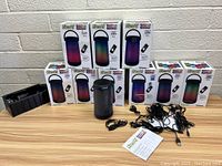 Lot of 10 LitexAll Spectrum Wireless LED Speaker Lights in boxes with power adapters, charging cables, and remotes.