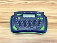 Front view of Brother P-touch label maker showing QWERTY keyboard, display screen, and print button.