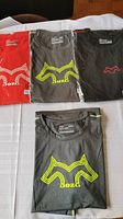 Four Dozer brand active workout shirts in original packaging laid out on a surface showing front logos in red, dark gray, and black colors.