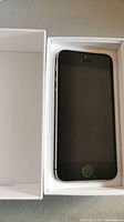 Front screen of iPhone SE in open white box, black screen, no visible cracks