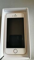 Front view of Apple iPhone SE in box showing screen and home button.
