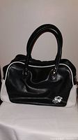 Front view of black and white gym bag with handles and detailing on smooth background.