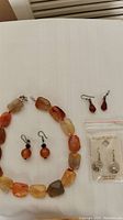 Jewelry pieces arranged on white surface showing gemstone necklace and earrings