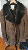 Front view of brown suede men's coat with large dark brown fur collar.