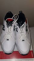 Pair of white New Balance running shoes with black and red details, laced, top view.