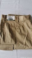 Folded khaki cargo pants showing the rear pocket with button and belt loops.