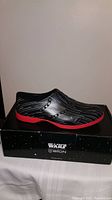 Side profile of black and red men's Star Wars BiiON shoe on top of the original packaging box with Star Wars branding.