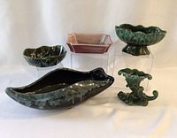 Five ceramic planters including three green leaf and floral shaped and one purple rectangular planter.