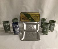 Overall lot showing Canadian Centennial tin container, eight drinking glasses, and two aluminum trays.