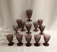 Full set of 13 Hazel Atlas Moroccan amethyst glass goblets arranged in rows showing their sizes and color consistency