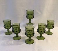 Front view of six green thumbprint glasses arranged in two rows on white background.