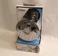 Front view of showerhead in original box showing chrome finish and multiple spray nozzles.