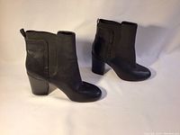 Side view of the pair of black leather ankle boots showing the smooth leather finish, block heel, and pull tab at the back.