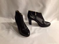 Side view of black leather ankle booties showing the shape, zipper, and heel.