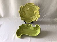 Two green Quebec Art Craft pottery pieces, a round plate with a raised bird in the center and a leaf-shaped dish below it.