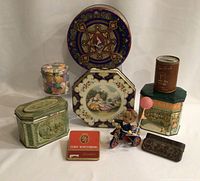 Photo of entire collection showing all tins and wind-up toy together on white background.