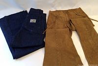 Two pairs of bell bottom pants side by side: dark blue denim and brown suede, showing shape and flare.