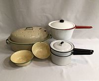 Overview photo showing all items in the lot: large covered roaster, two saucepans with lids, two bowls.