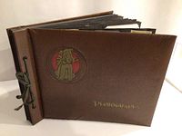Closed view of the brown leather-like textured cover album with a dog motif and 'Photographs' label.