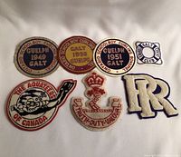 Seven vintage patches laid flat on white cloth surface showing curling association patches, military crest, fish emblem, and letter patch.
