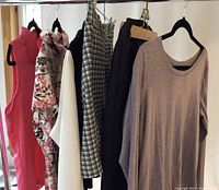 Photo showing various women's golf clothing on hangers including a pink sleeveless golf shirt, floral short-sleeve shirt, beige and black pants, checked pants, and a beige Lululemon long-sleeve shirt.