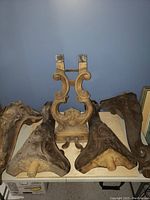 Photo of four antique carved wooden organ legs showing their floral and scrollwork design and threaded pegs for attachment.