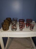 Full lot of colorful vintage printed drinking glasses including various styles of short tumblers and shot glasses
