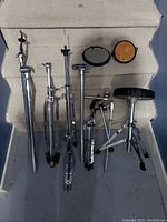 All drum hardware items including cymbal stands, drum throne, and practice pads arranged on stairs.