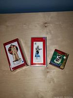 Photo showing all three Elvis Presley Christmas ornaments in original packaging, displayed on a wooden surface.