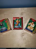 Three boxed Elvis Presley Christmas ornaments displayed on a wooden surface.