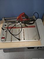 Overall view of SKIL flooring saw on table showing base and saw with cord.