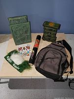 Overview of all lot items on table showing jewelry boxes, backpack, didgeridoo, tattoo stickers, and Carlsberg pouch with feathers