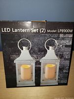 Photo of the boxed LED lantern set with model number LP8900W and image of two white lanterns with glass panels and handles.