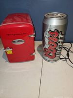 Closed red Frigidaire mini fridge next to a Coors Light beer can for size comparison.