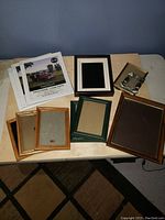 Overview of various picture frames grouped on a table showing multiple sizes and styles including wood and metal frames.