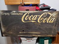 Metal Coca-Cola sign with visible weathering and rust marks, showing 'Enjoy/Savourez Coca-Cola'