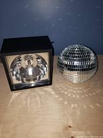 Front view of black strobe light with reflective dome and disco ball sphere beside it